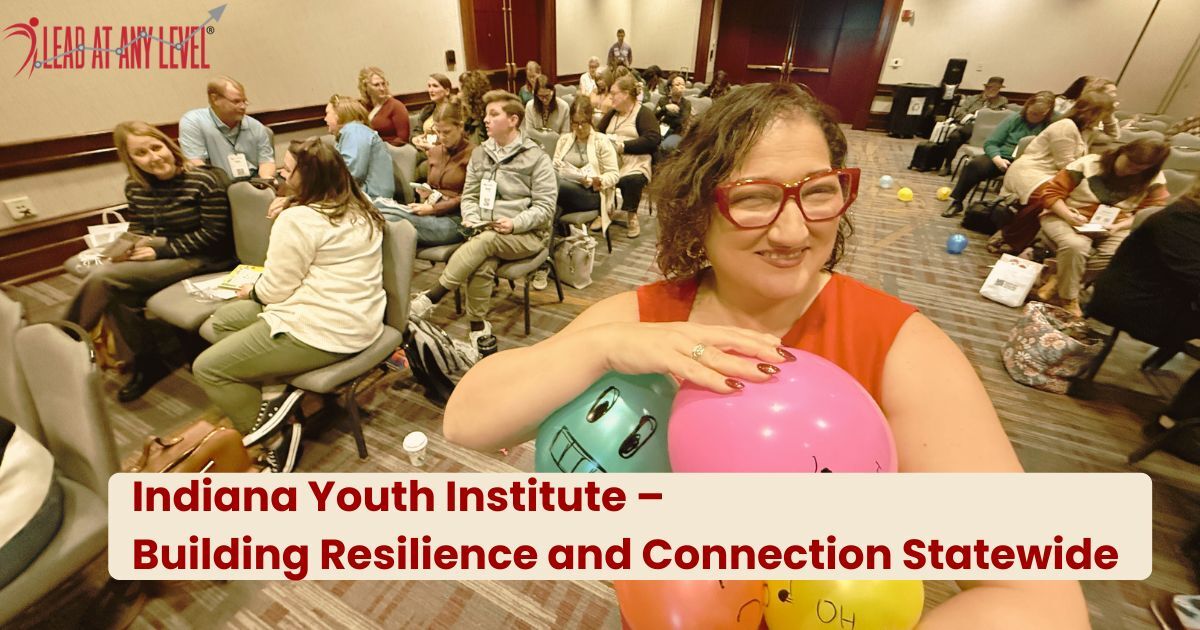 Amy Waninger holds an armful of colorful  balloons  with an IYI Kids Count Conference audience in the background